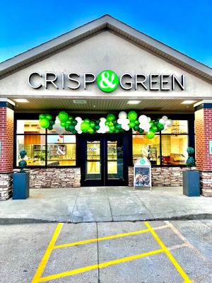 CRISP & GREEN storefront decorated with green and white balloons outside a strip mall.