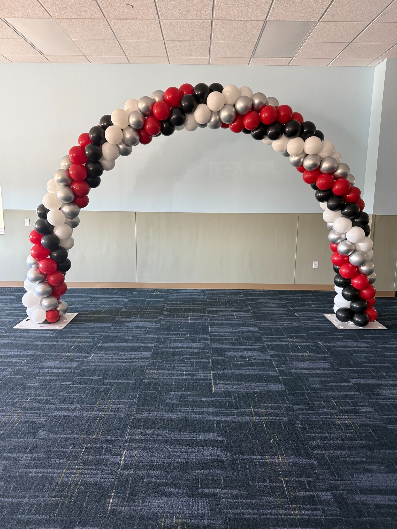 Red, black, white, and silver balloon arch installed in an event room