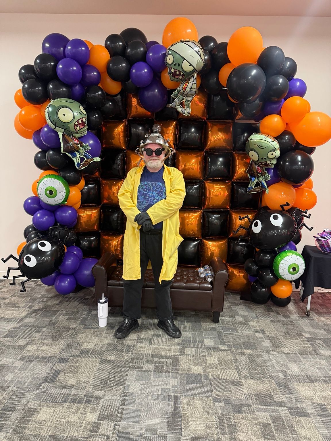 Orange and black checkerboard balloon wall framed by purple balloons and Halloween characters