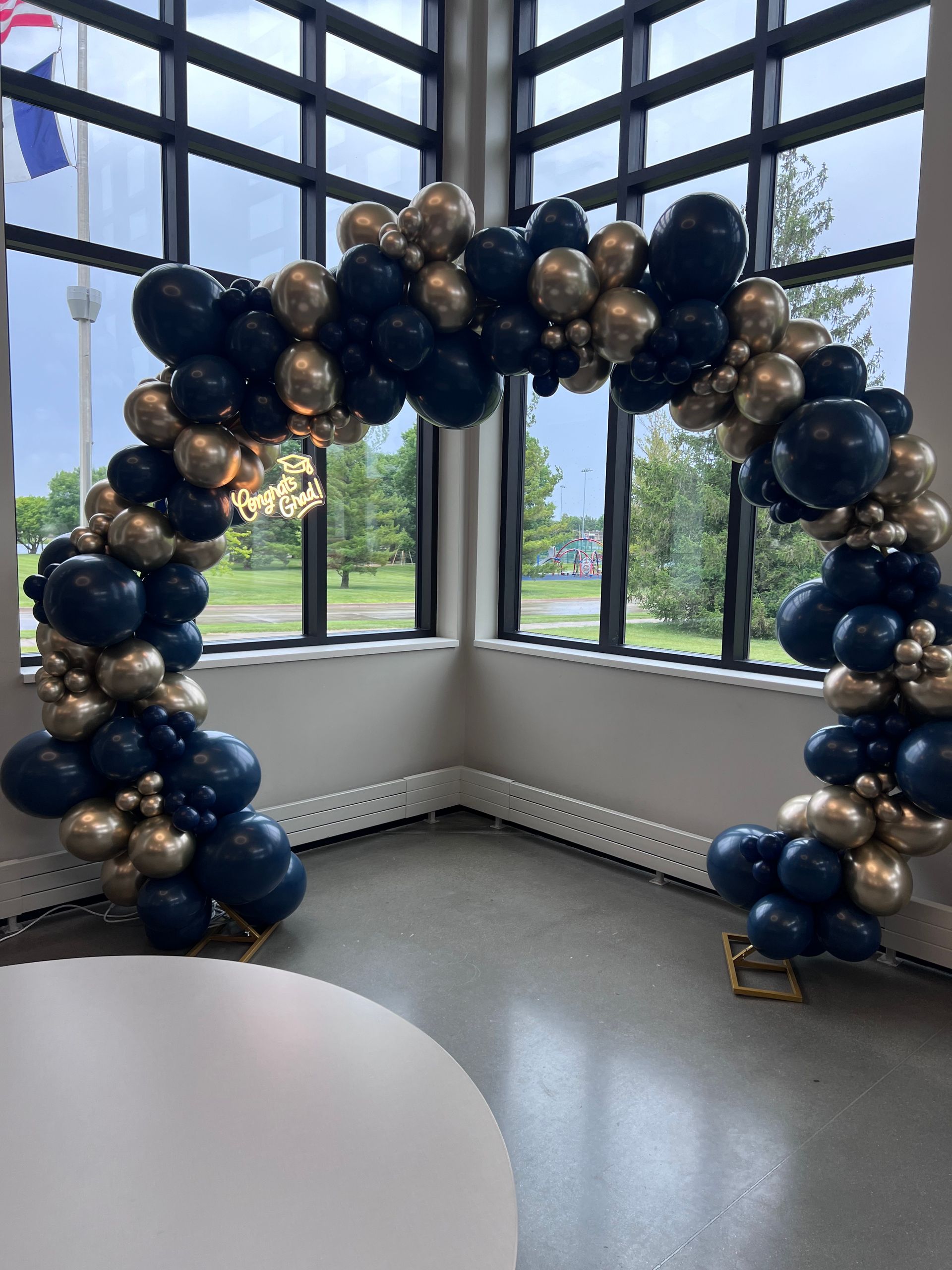 Navy, ivory, and gold organic balloon arch positioned beside a bright window.
