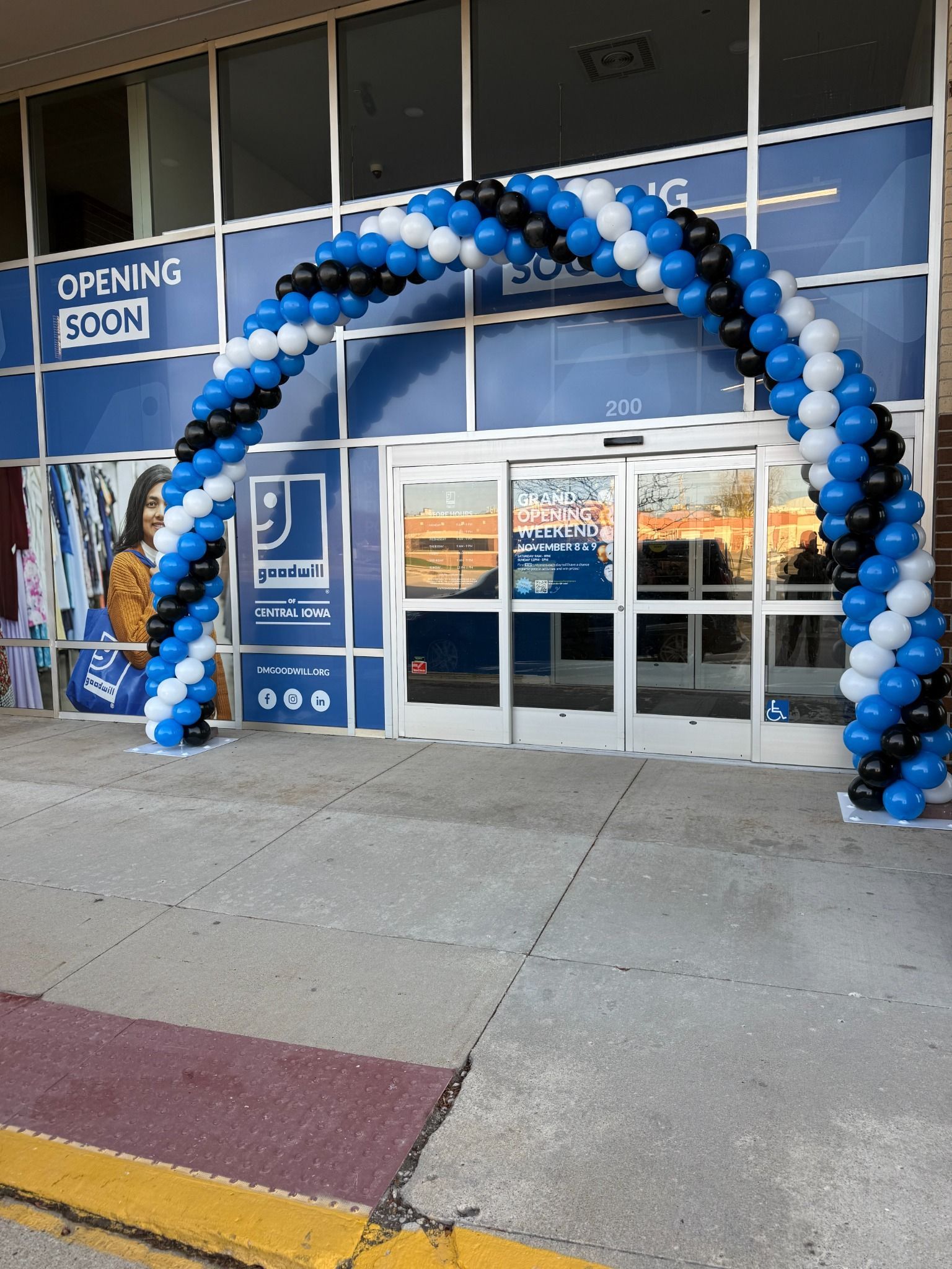 Blue, white, and black balloon arch framing a storefront