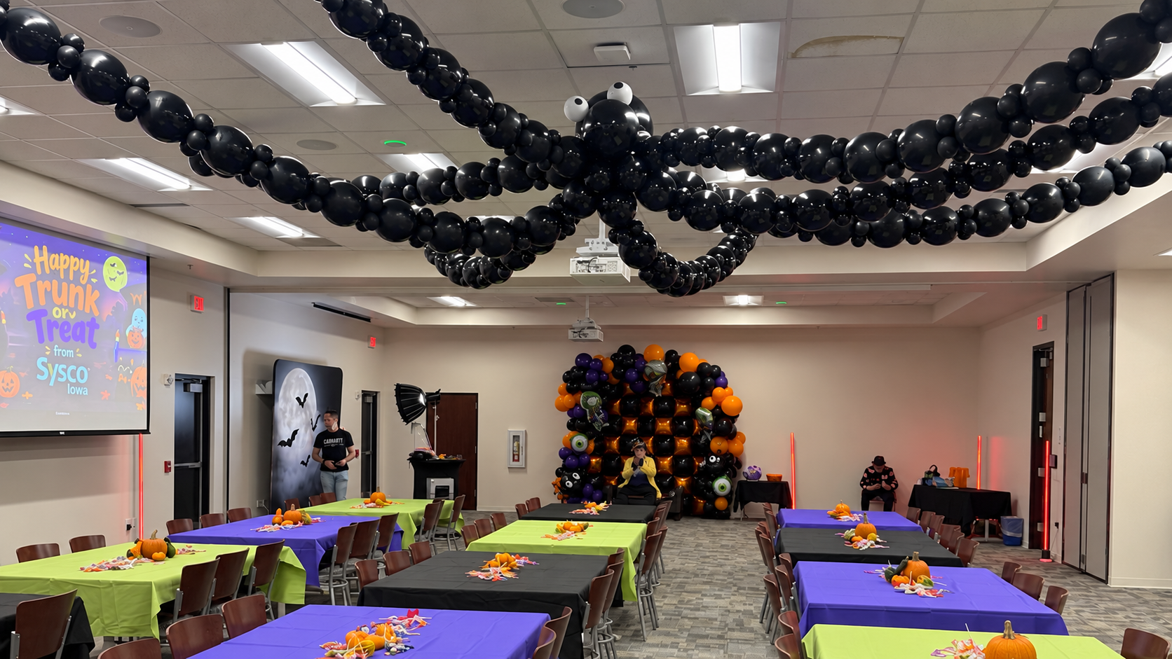 Giant black balloon spider and Halloween photo backdrop at Sysco Iowa’s trunk-or-treat event by Squeak Balloon & Decor