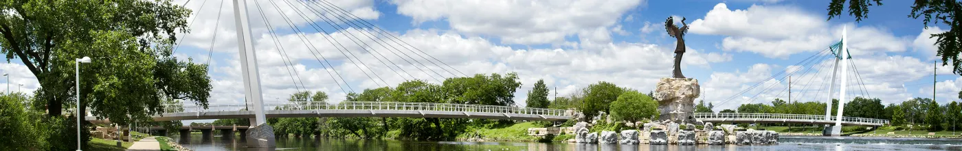 A blurry picture of a bridge over a river with trees in the foreground and a statue in the background.