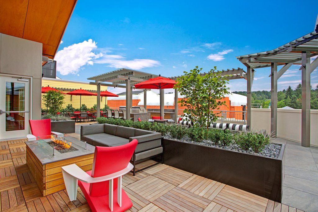 A patio with a fire pit, couch, chairs, and umbrellas at Woodin Creek Village.