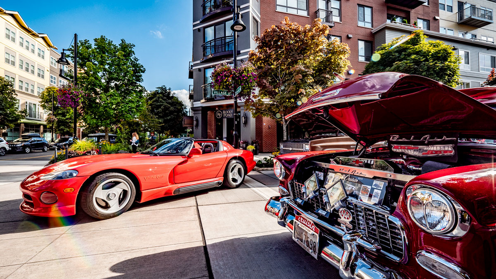Two red sports cars are parked next to each other on a city street.
