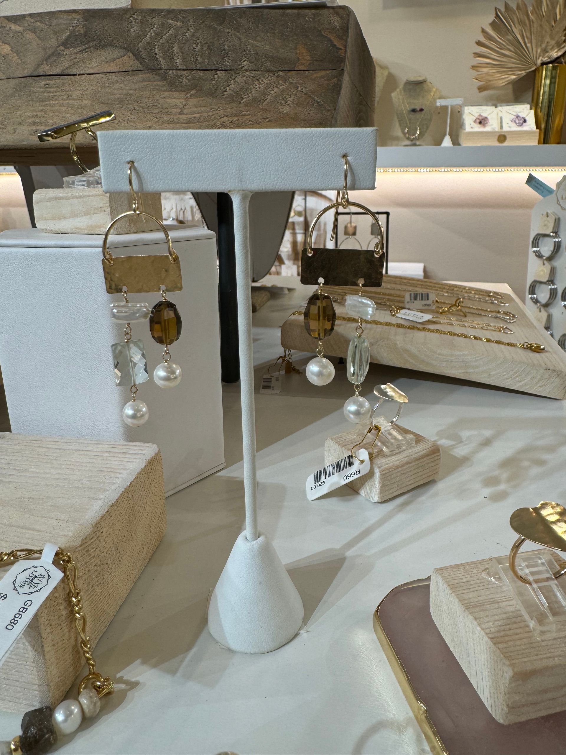 A pair of earrings sitting on top of a white stand