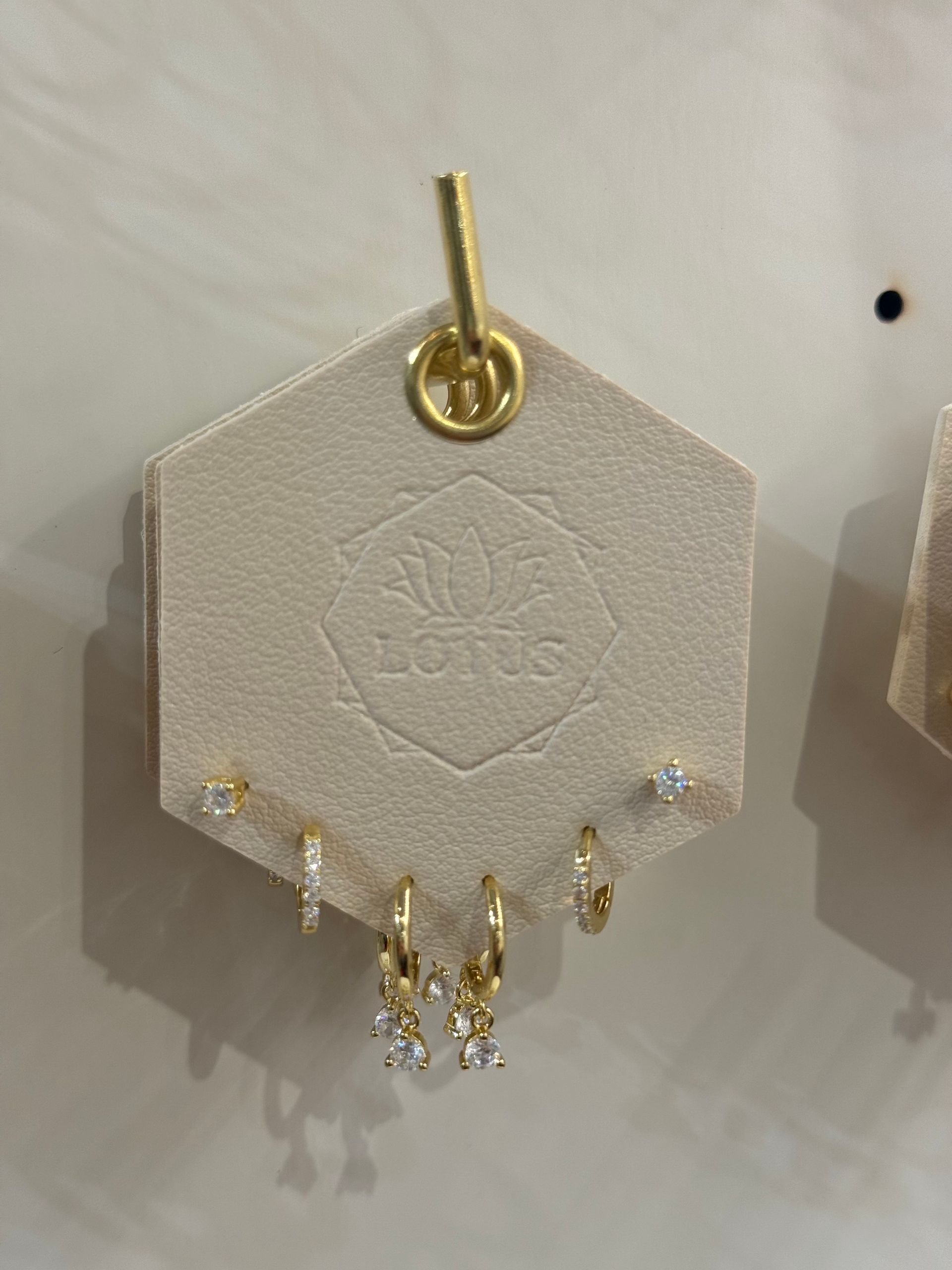 A pair of gold hoop earrings are displayed on a card