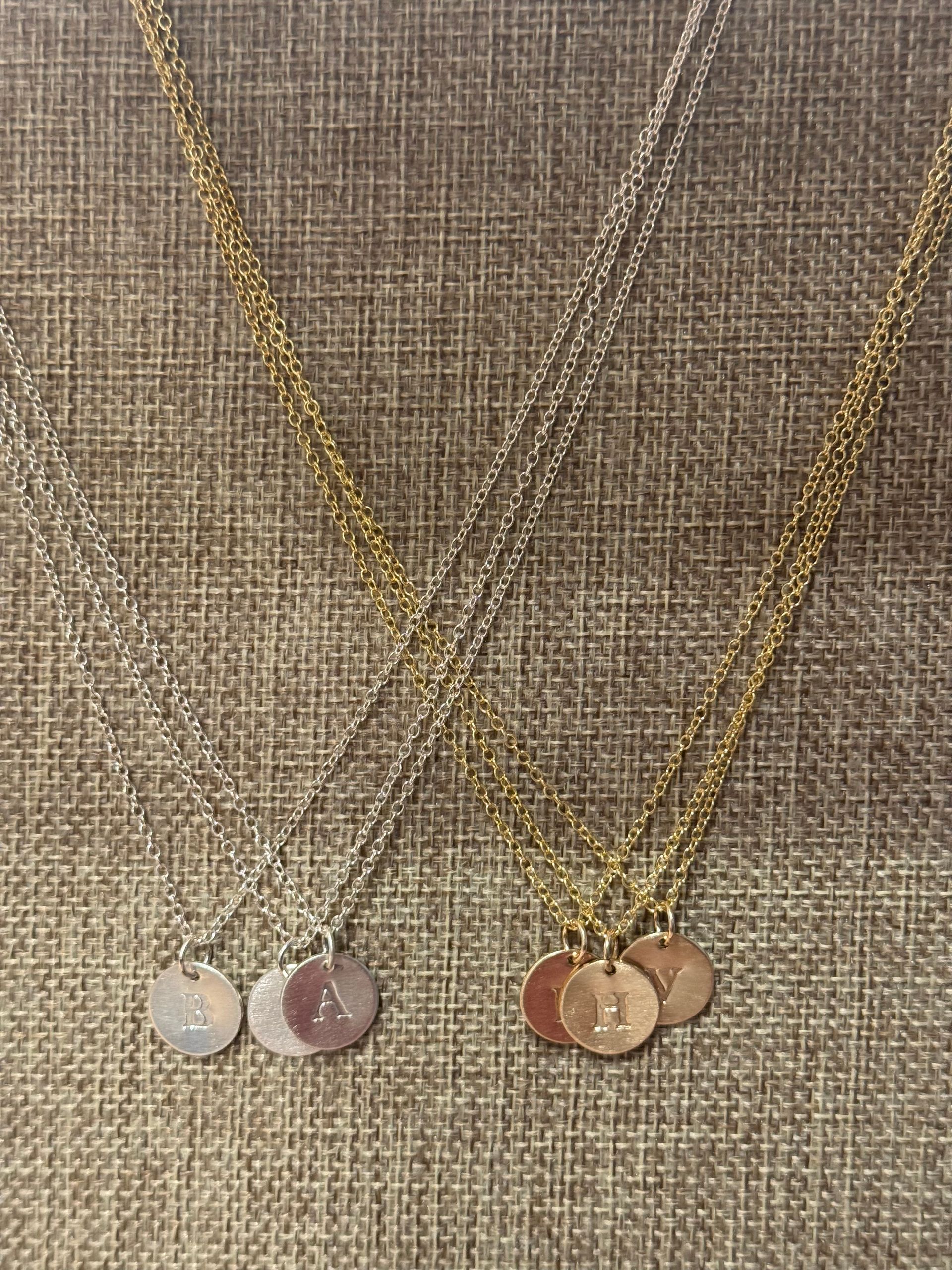Three necklaces are sitting on top of each other on a table.