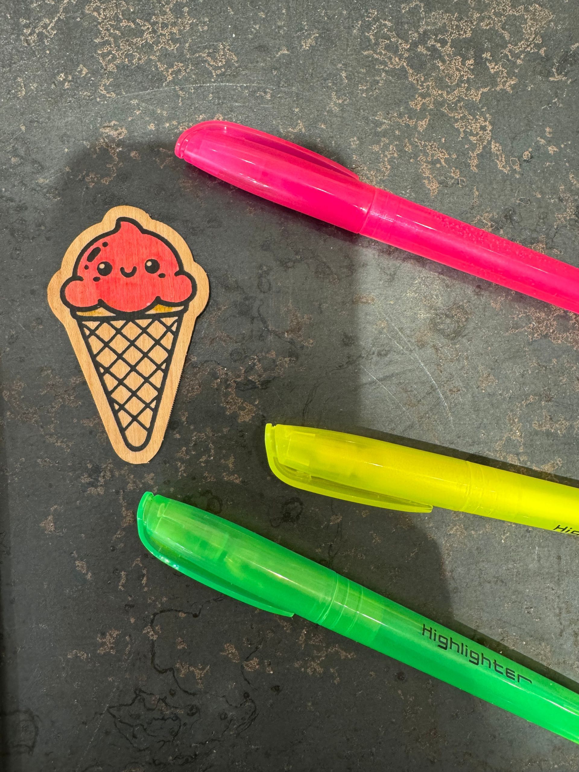 A sticker of an ice cream cone next to three pens