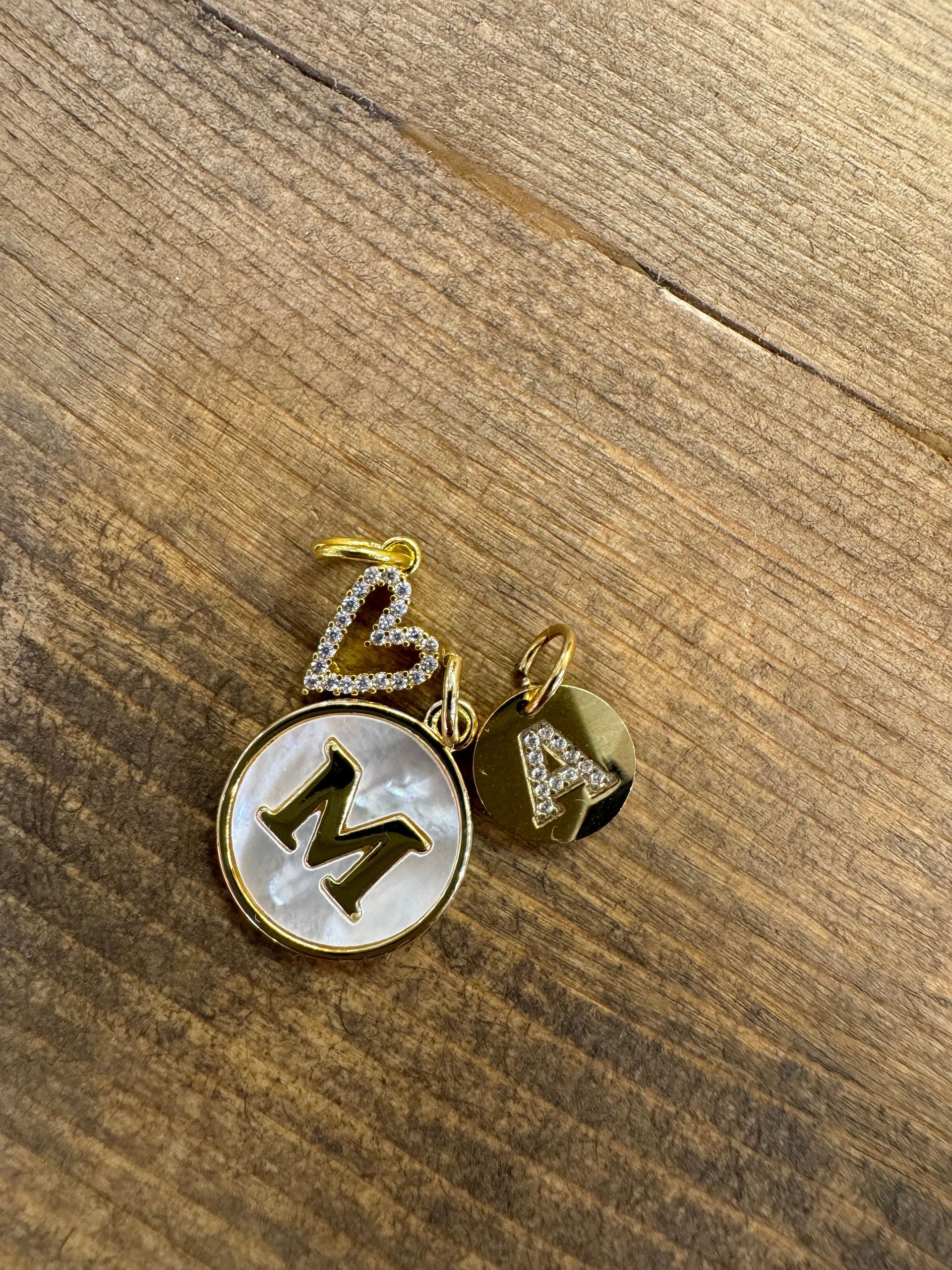 A necklace with the letter m on it is sitting on a wooden table.