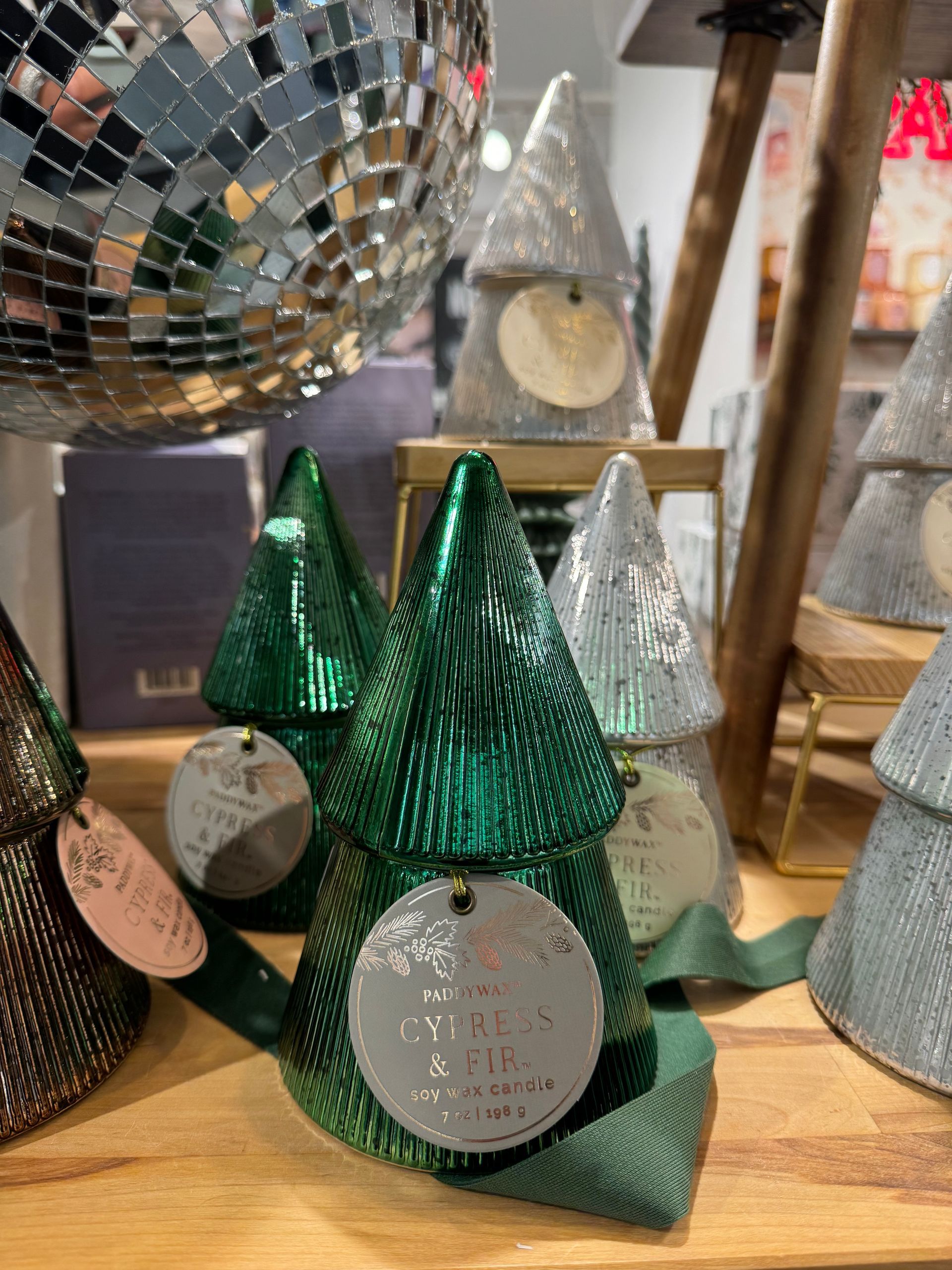 A display of christmas trees on a table with a disco ball in the background