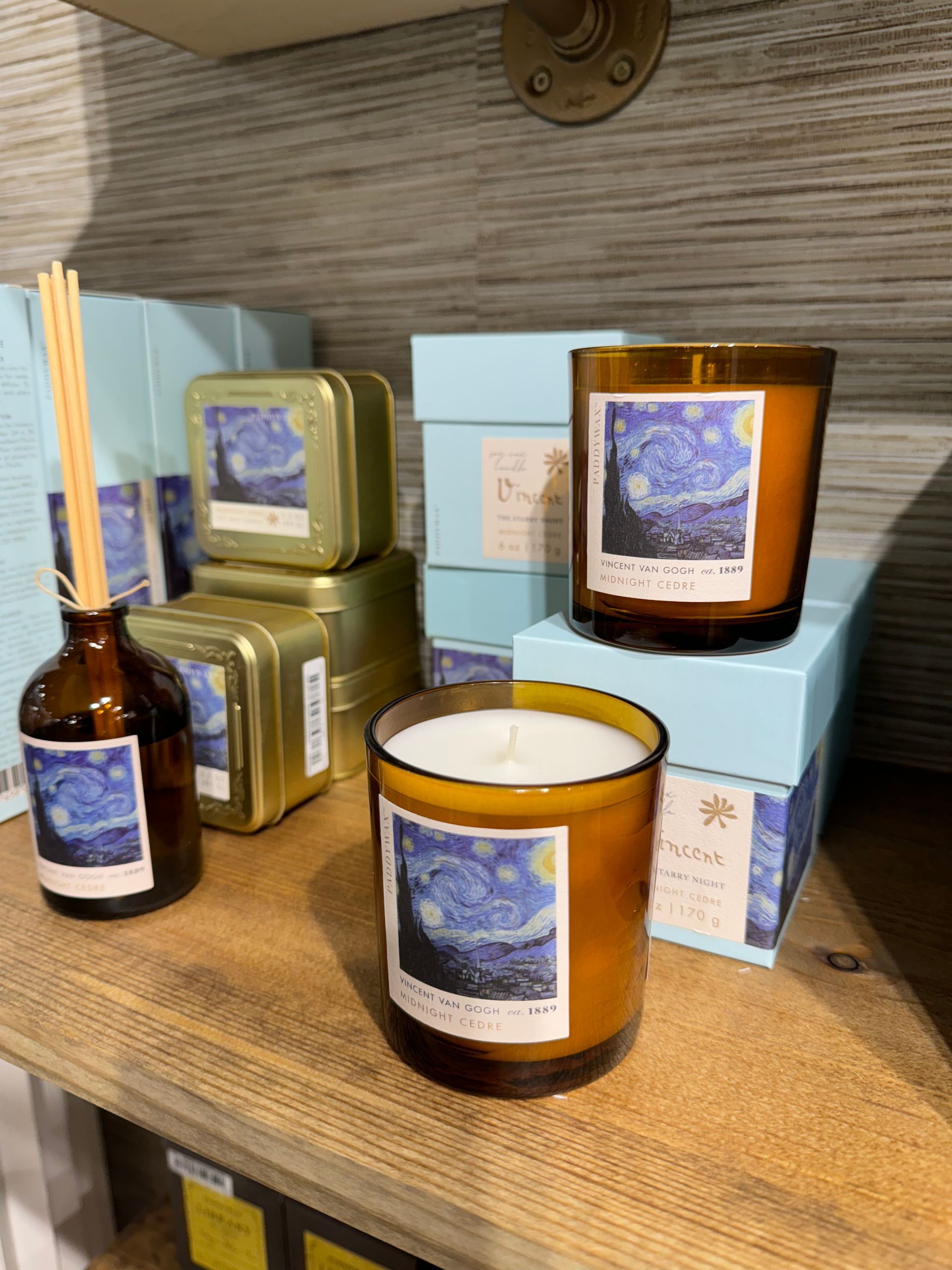 A starry night candle is on a shelf with other candles