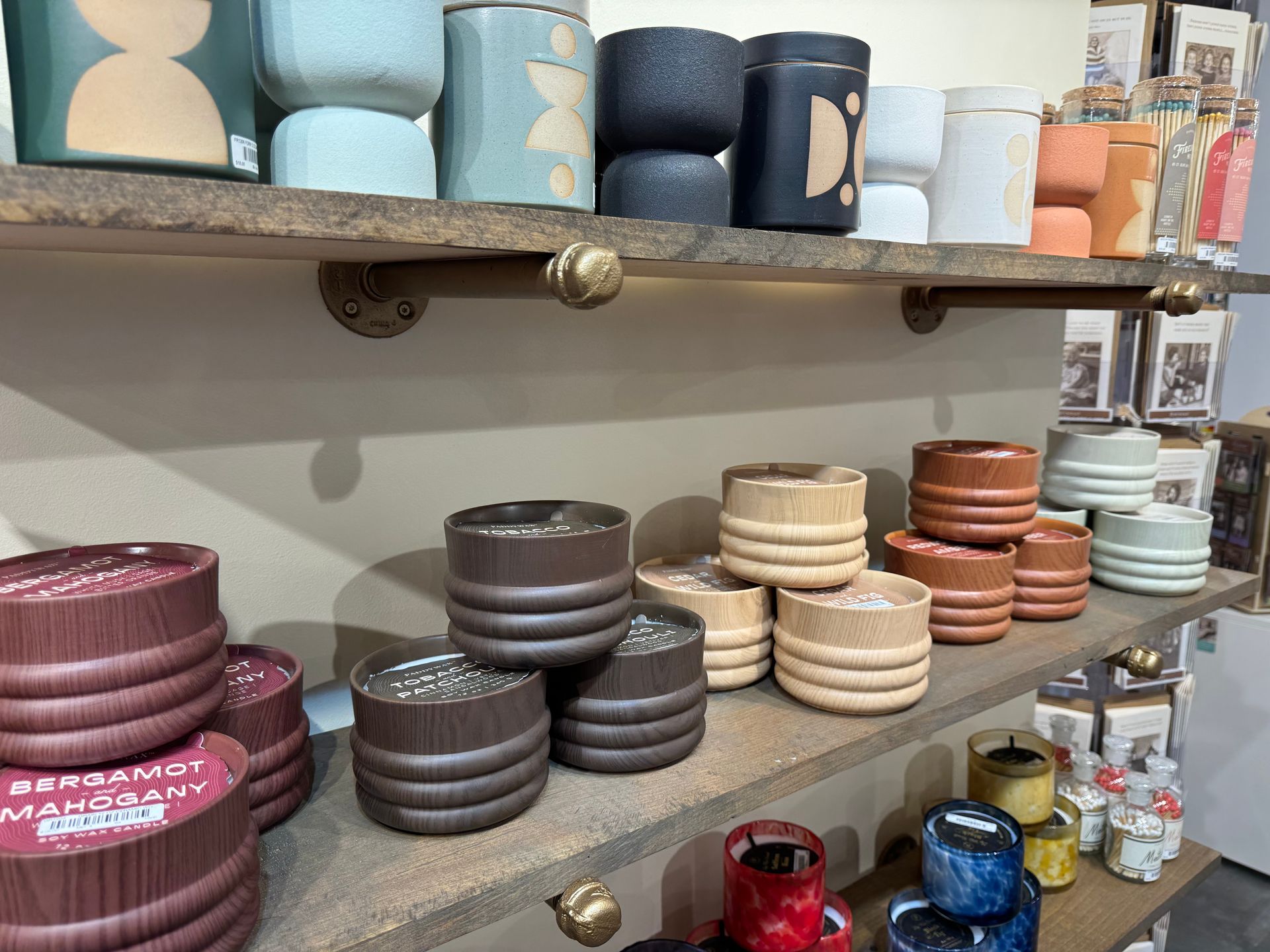 A variety of candles are displayed on shelves in a store