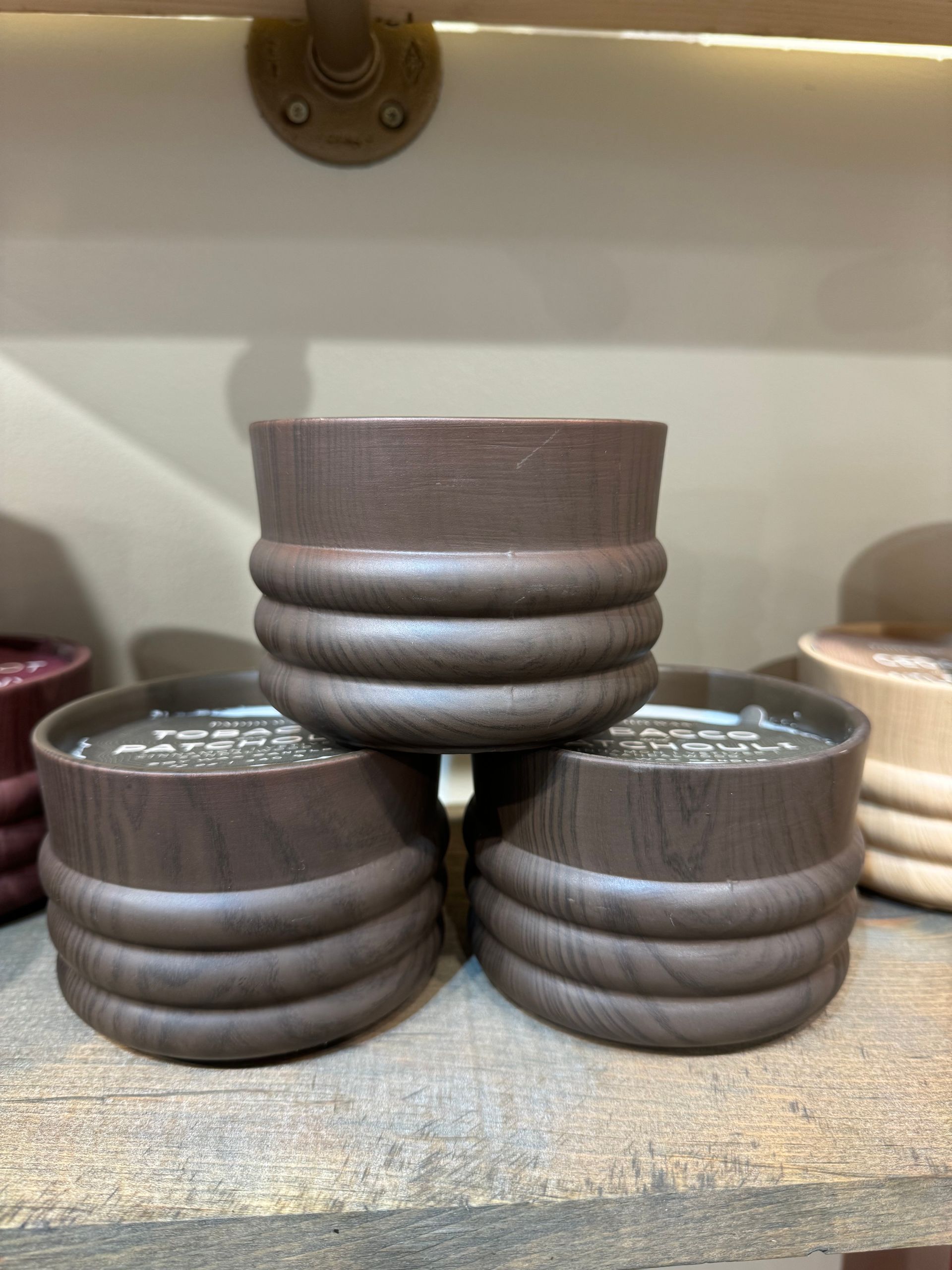 Three wooden bowls are stacked on top of each other on a wooden shelf.