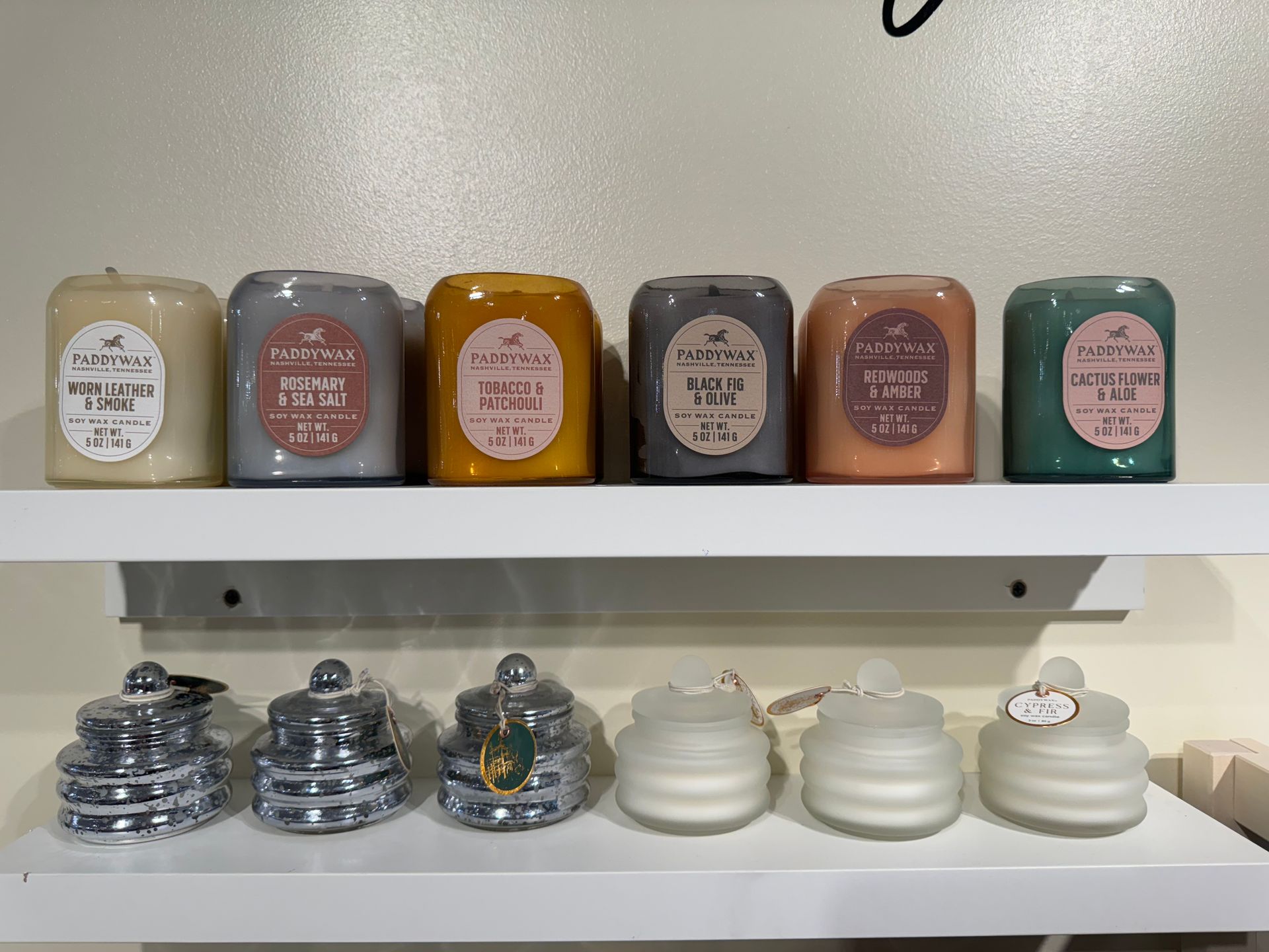 Several candles are lined up on a white shelf