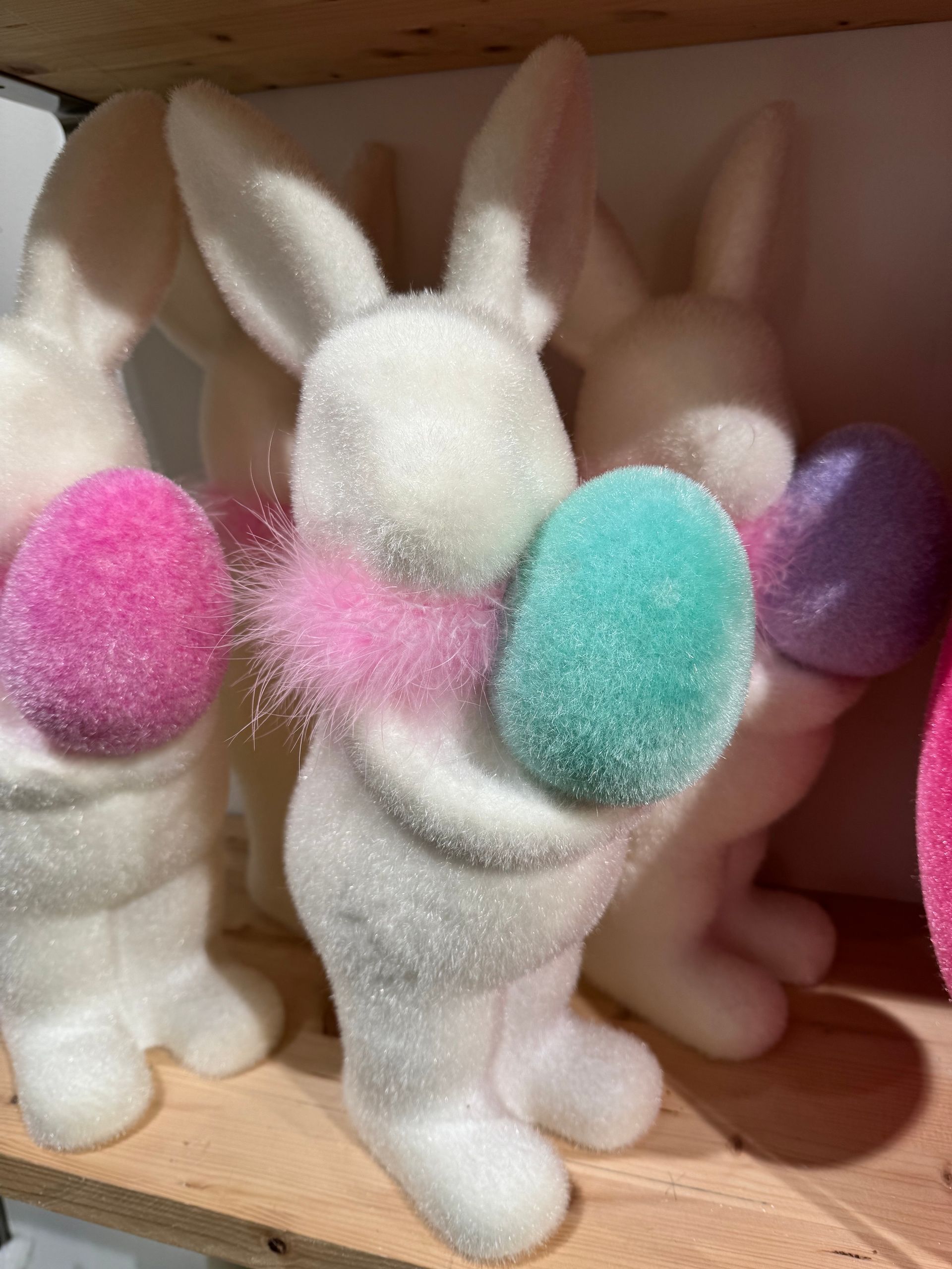 A white bunny holding a pink and blue easter egg