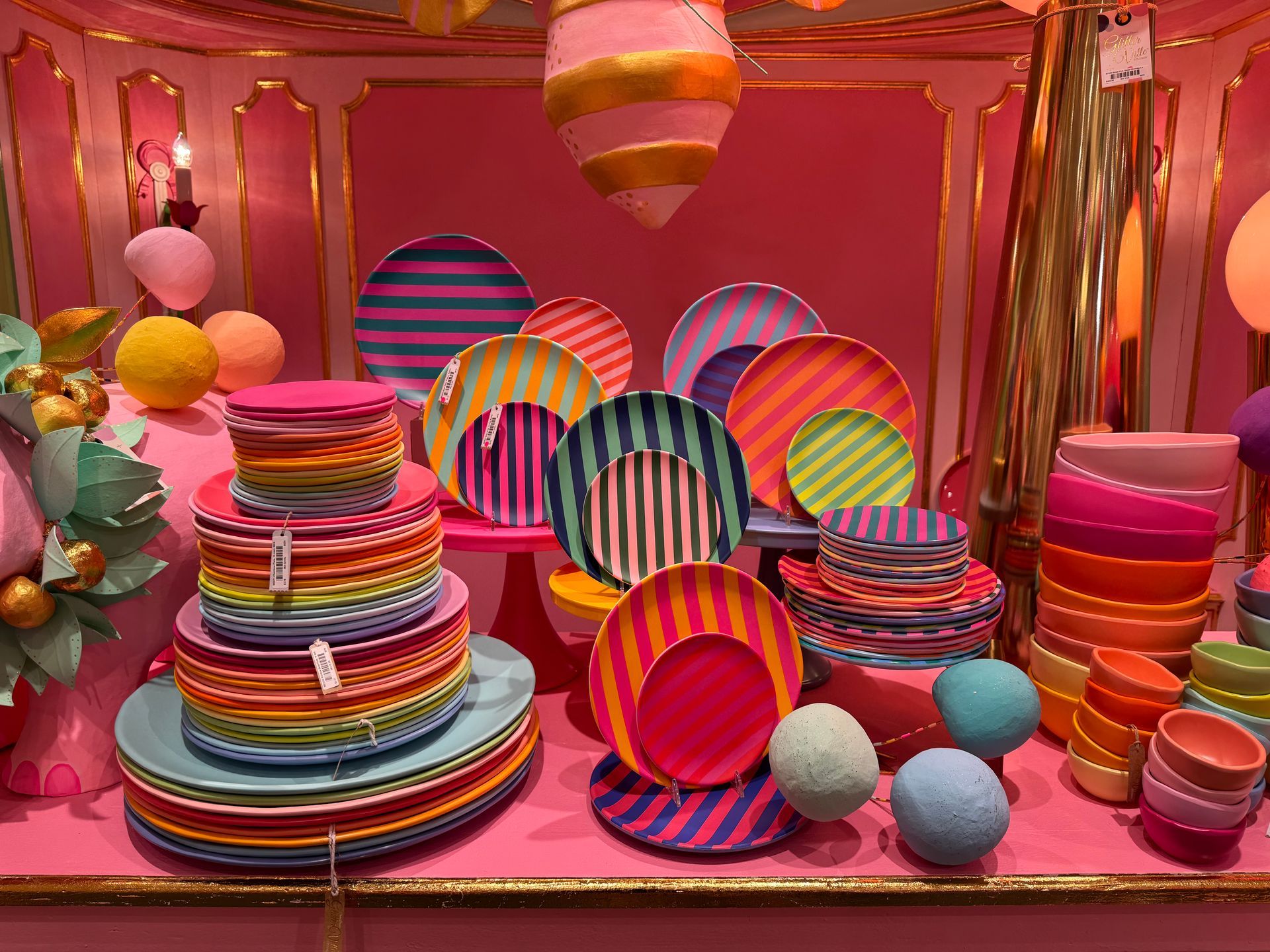 A display of colorful plates and bowls in a pink room