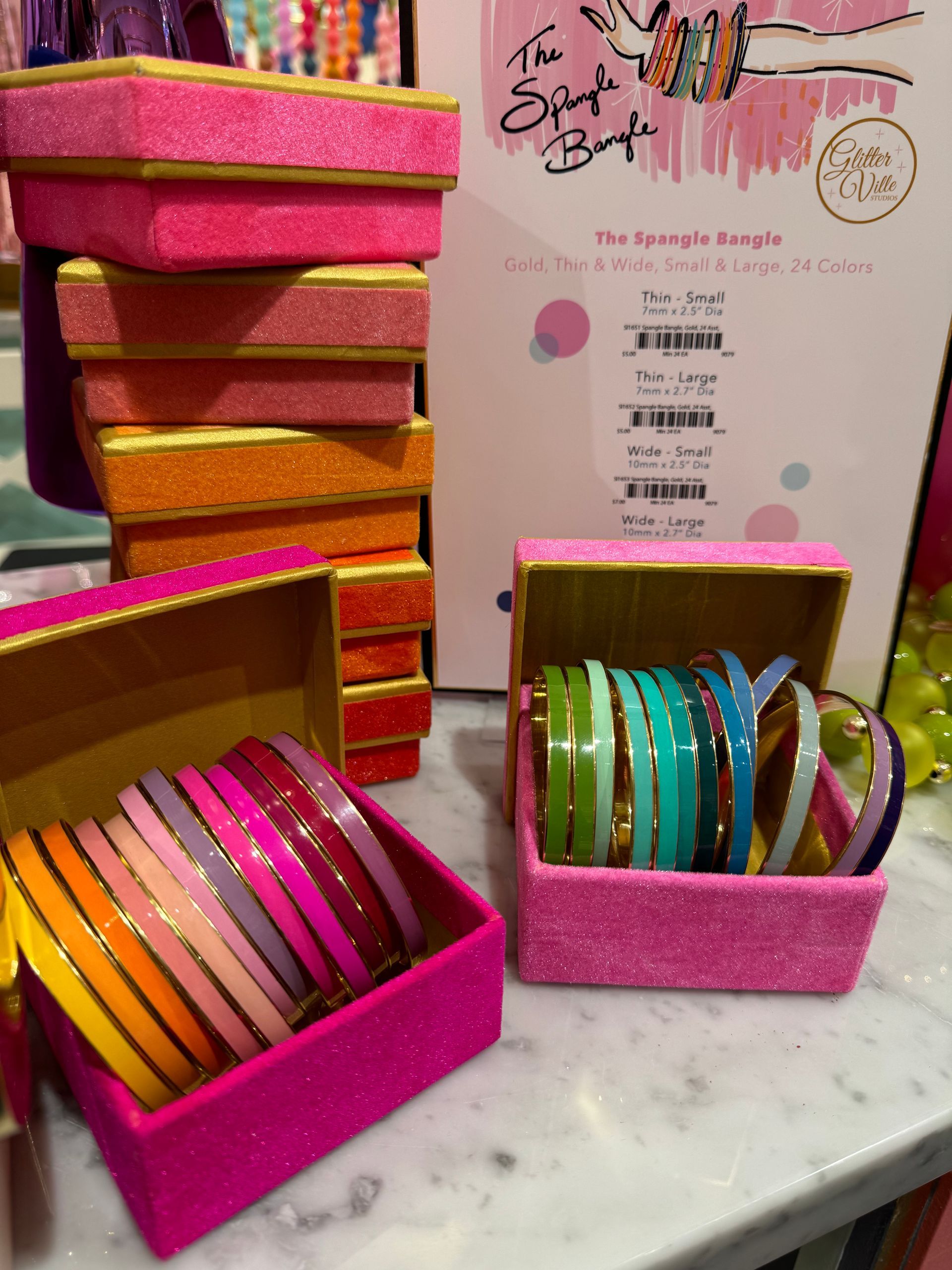 A stack of pink boxes with bracelets in them