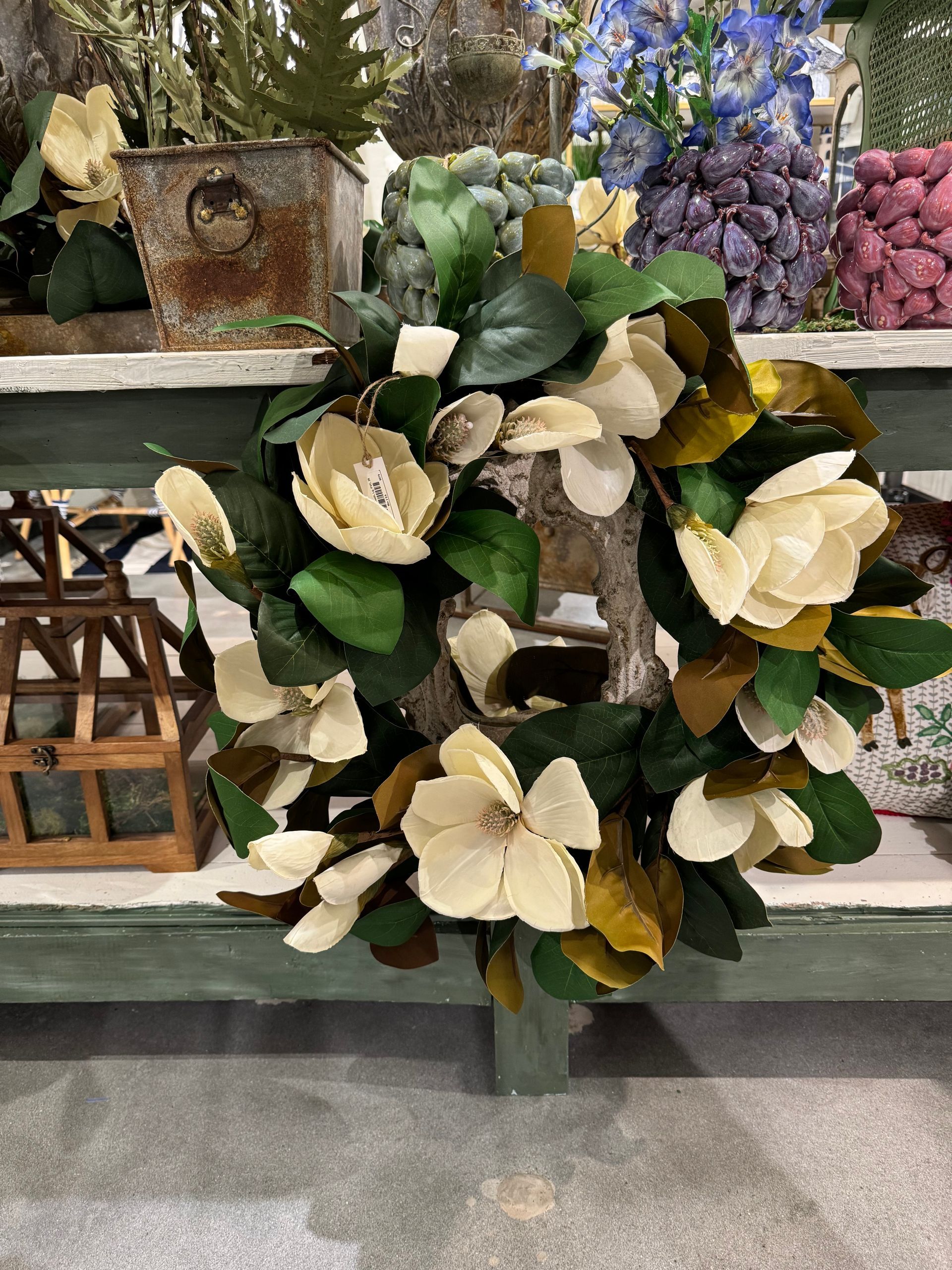 A wreath with white flowers and green leaves is sitting on a table.