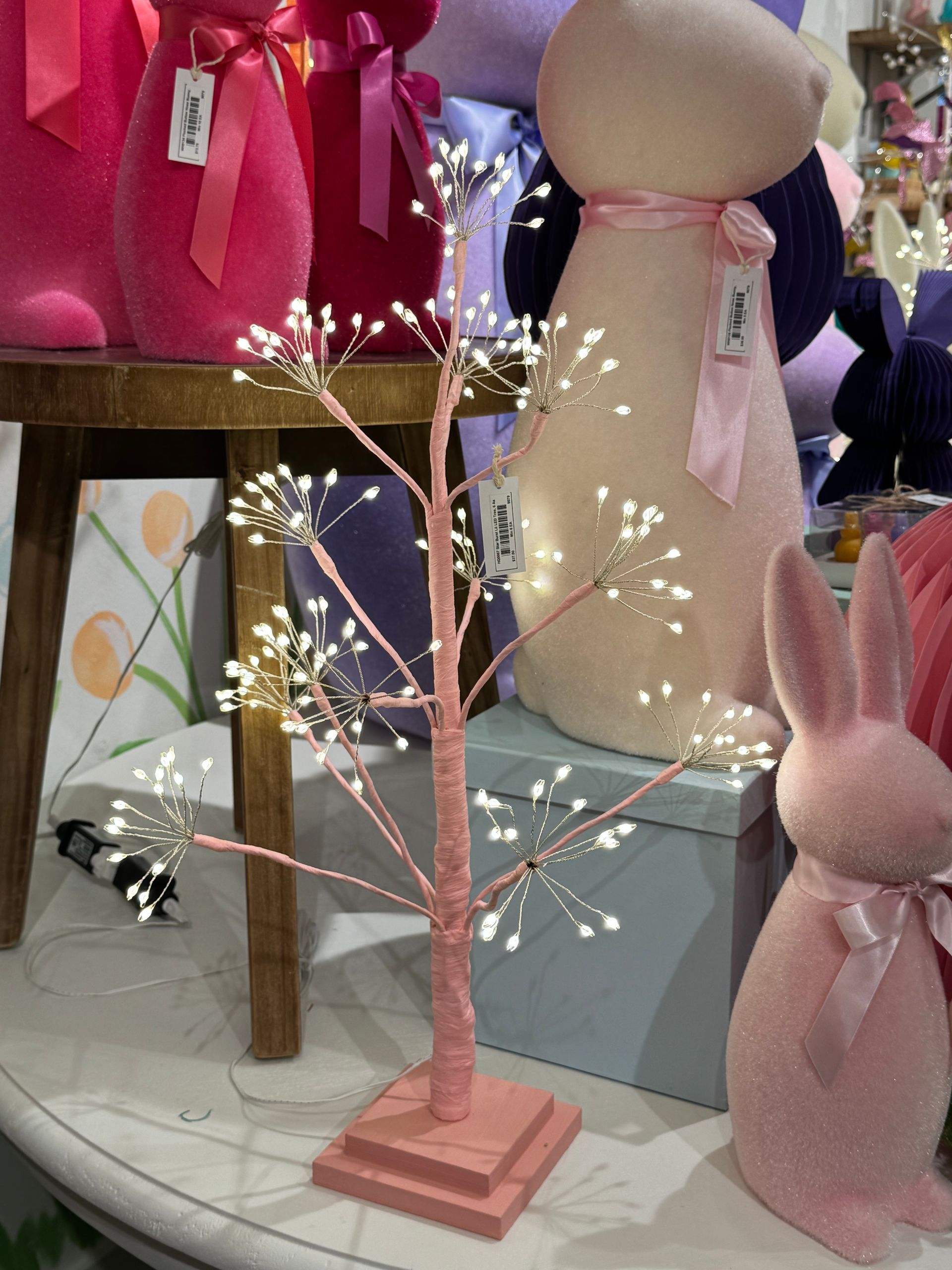 A pink bunny is sitting next to a pink tree