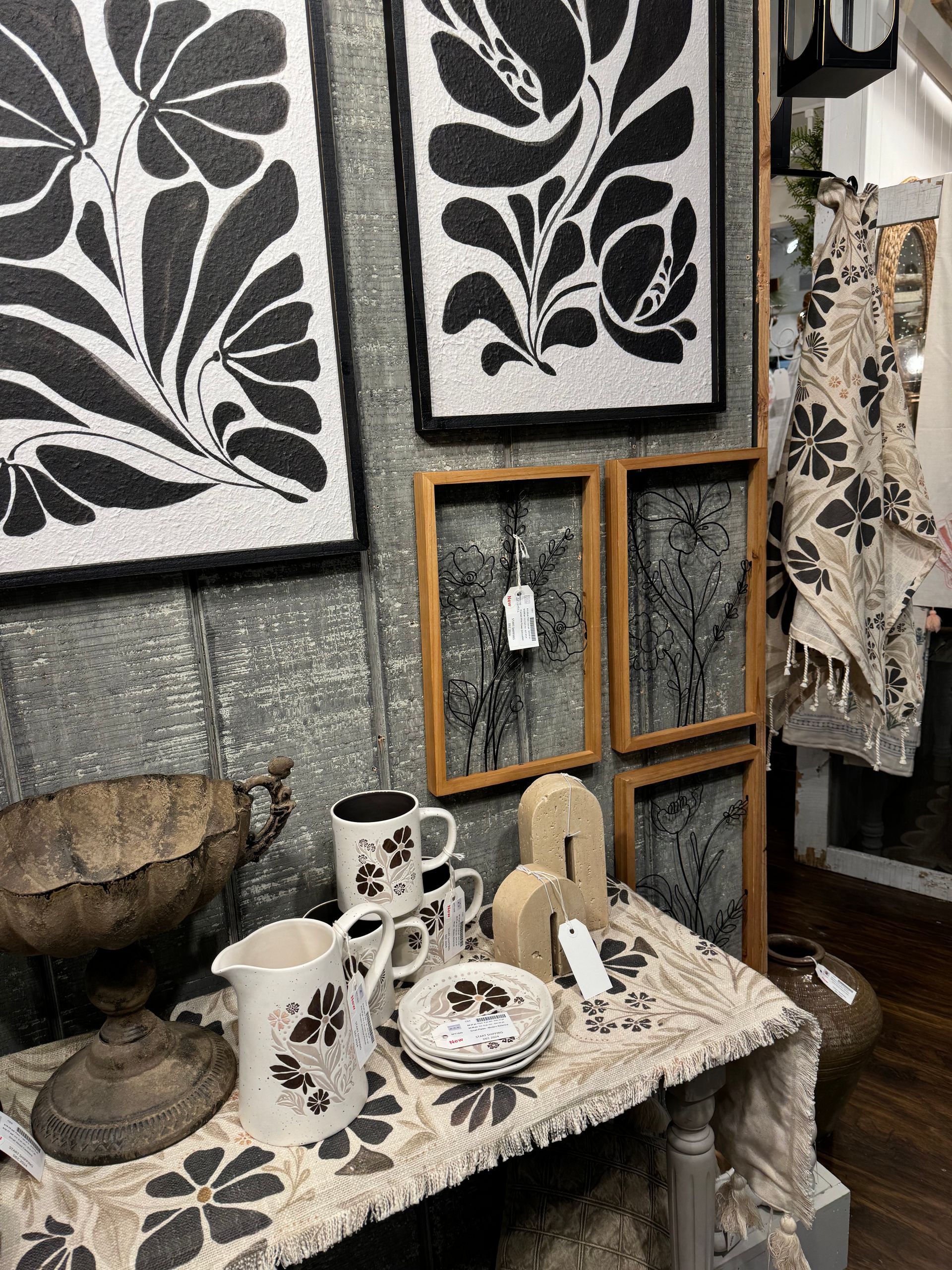 A table with plates and mugs on it and a wall with paintings on it.
