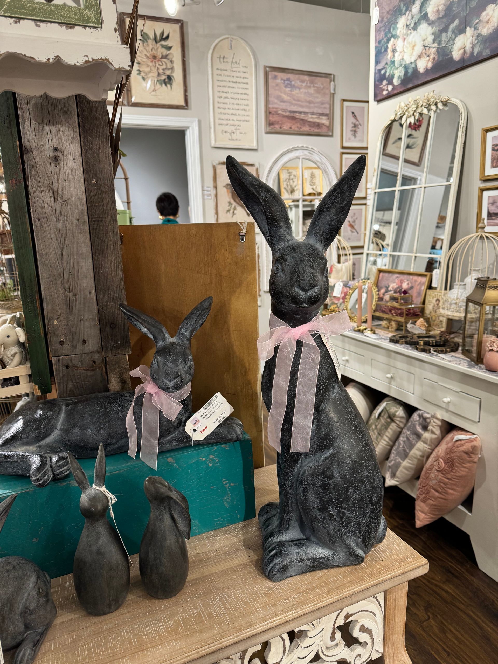 A black rabbit with a pink bow is sitting on a table