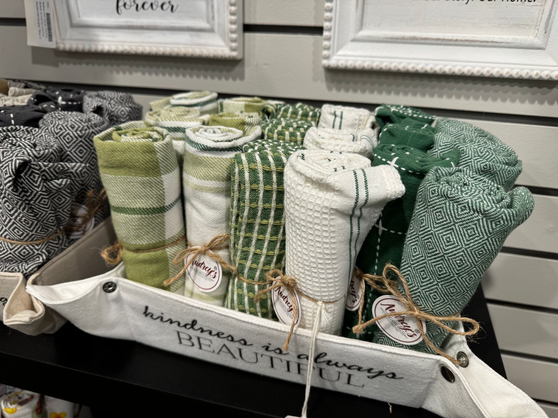 A basket filled with green and white towels on a shelf.