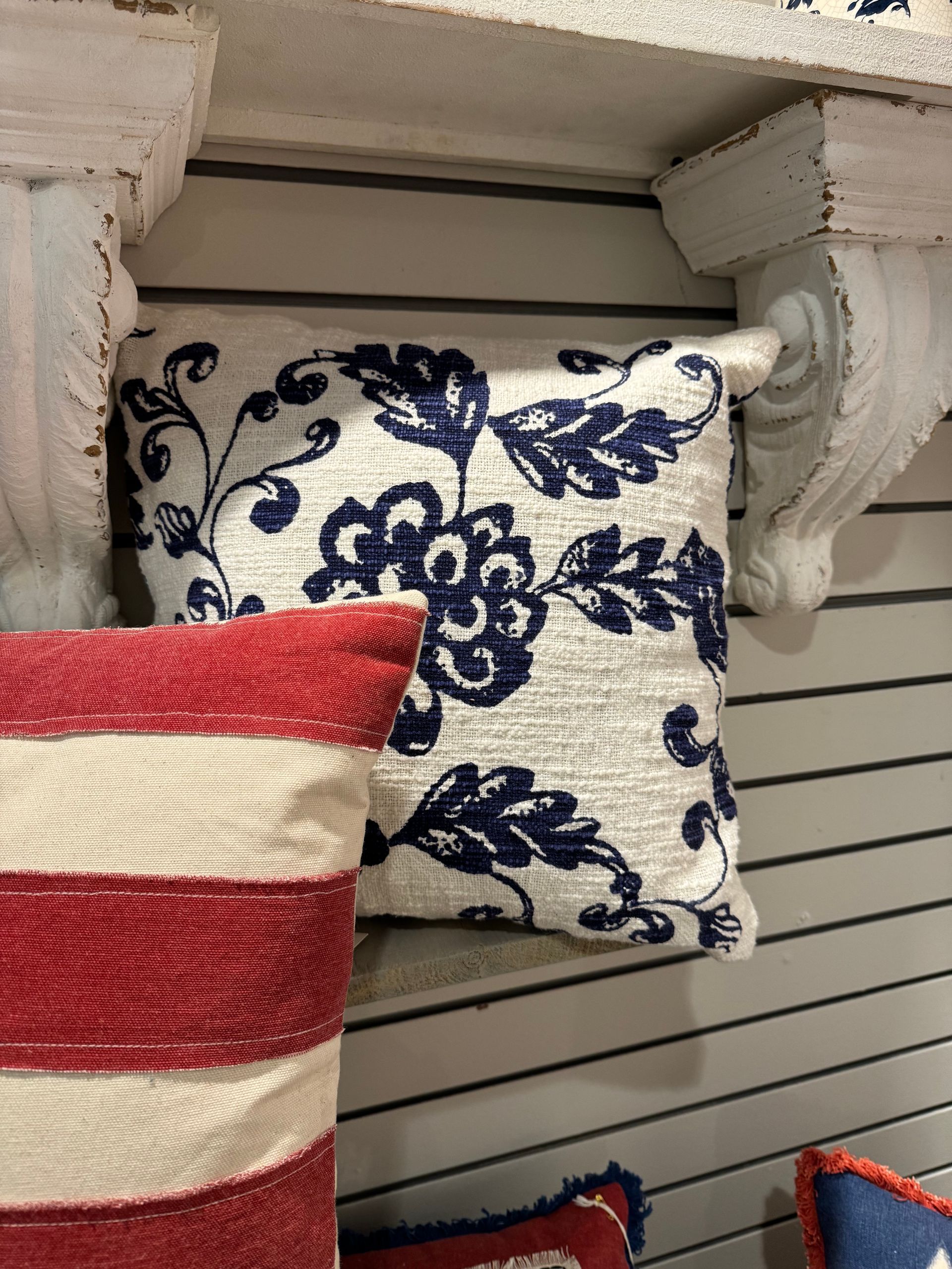 A red white and blue pillow is sitting on a shelf