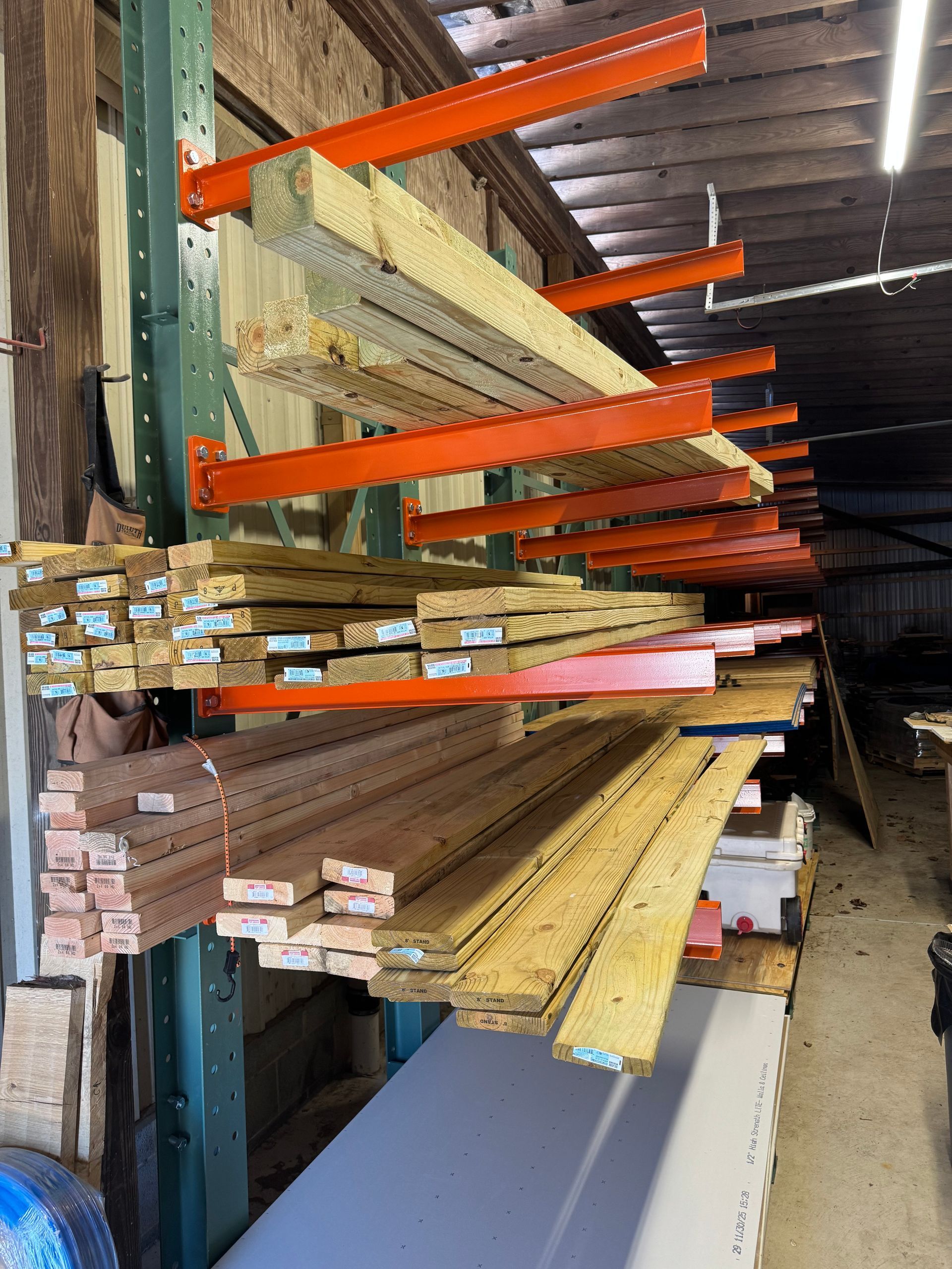 Lumber storage rack with various wood planks and beams in a warehouse setting.