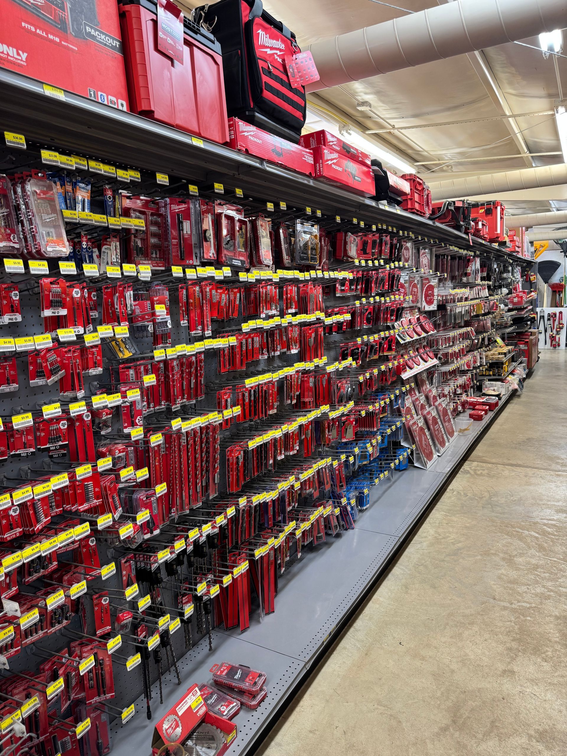 Shelves stocked with red Milwaukee tools in a store setting.