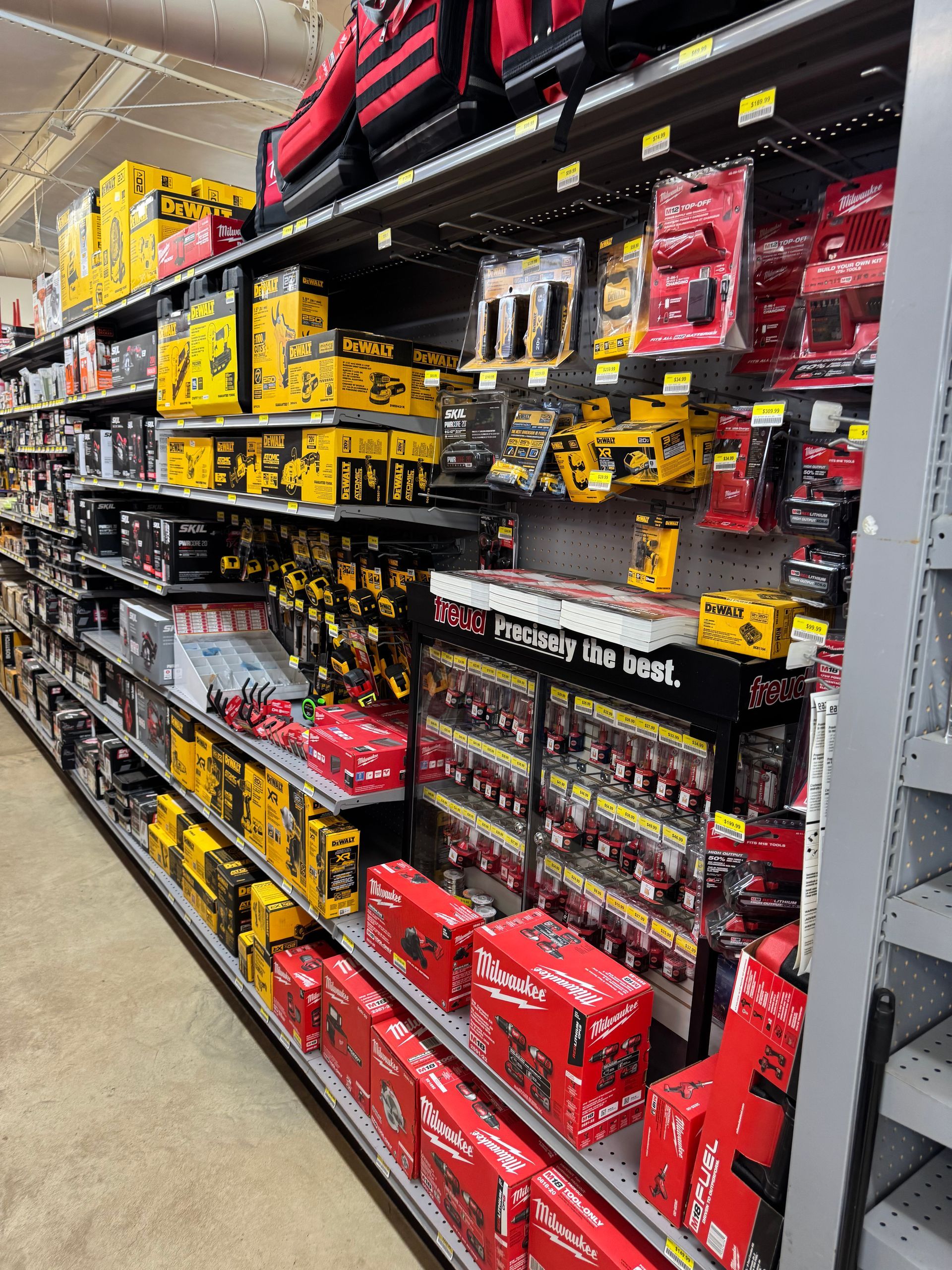 Shelves in a hardware store stocked with yellow and red power tools and accessories.