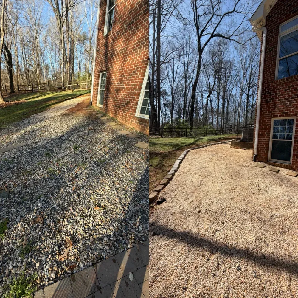 Gravel path beside a brick house on a wooded slope, with bare trees and winter sunlight.