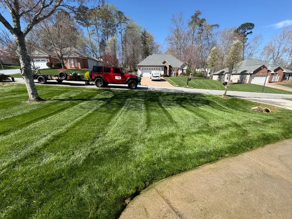 Red pickup truck parked by a suburban house with freshly striped green lawn on a sunny day