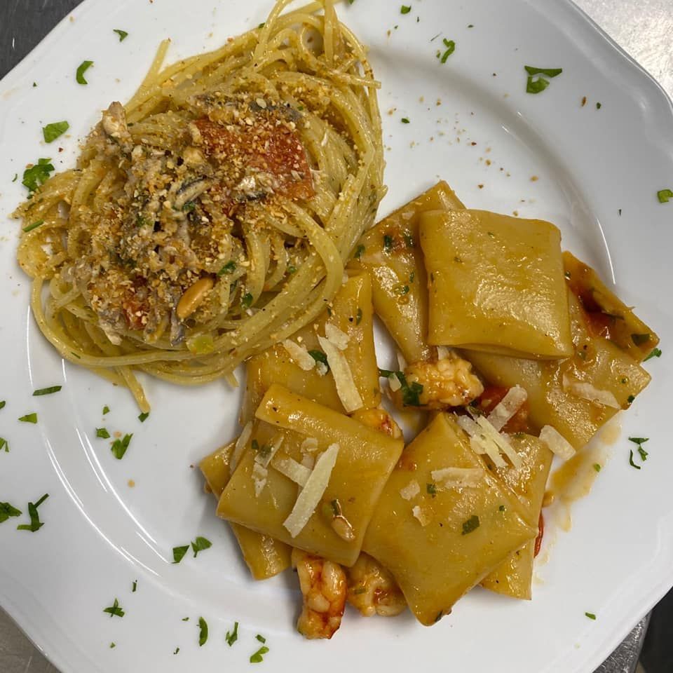 Piatto di pasta: spaghetti al sugo e paccheri al sugo, guarnito con prezzemolo e formaggio.