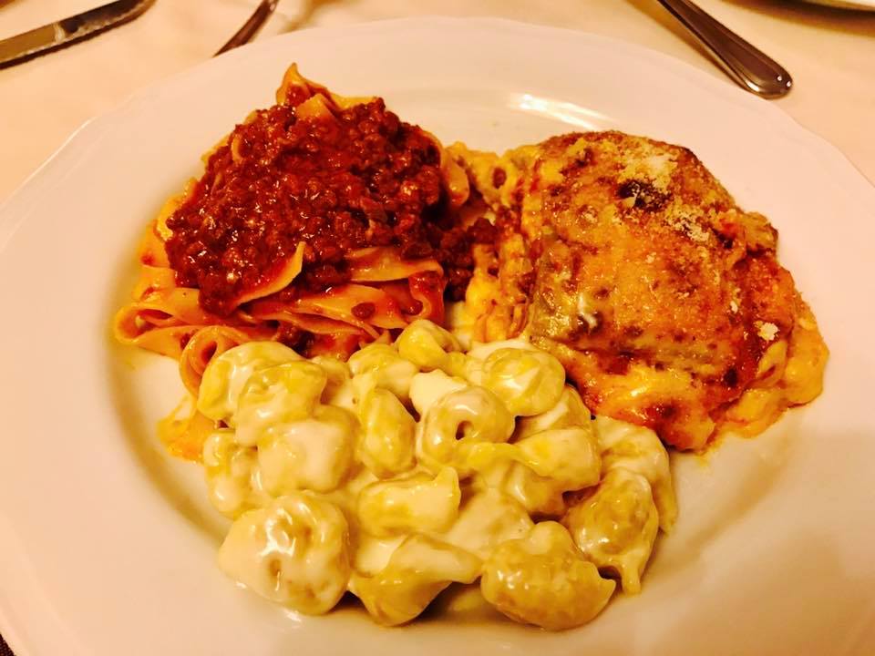 Trio di pasta: pappardelle al ragù, maccheroni al formaggio e lasagna su un piatto bianco.