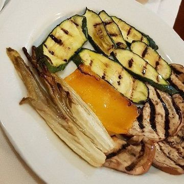 Verdure grigliate su un piatto bianco: zucchine, melanzane, peperone giallo e cipolla.