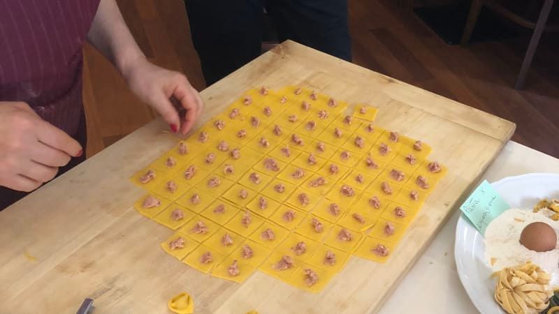 Ripieno rosa adagiato su una sfoglia di pasta rossa, pronto per essere piegato a formare i ravioli.