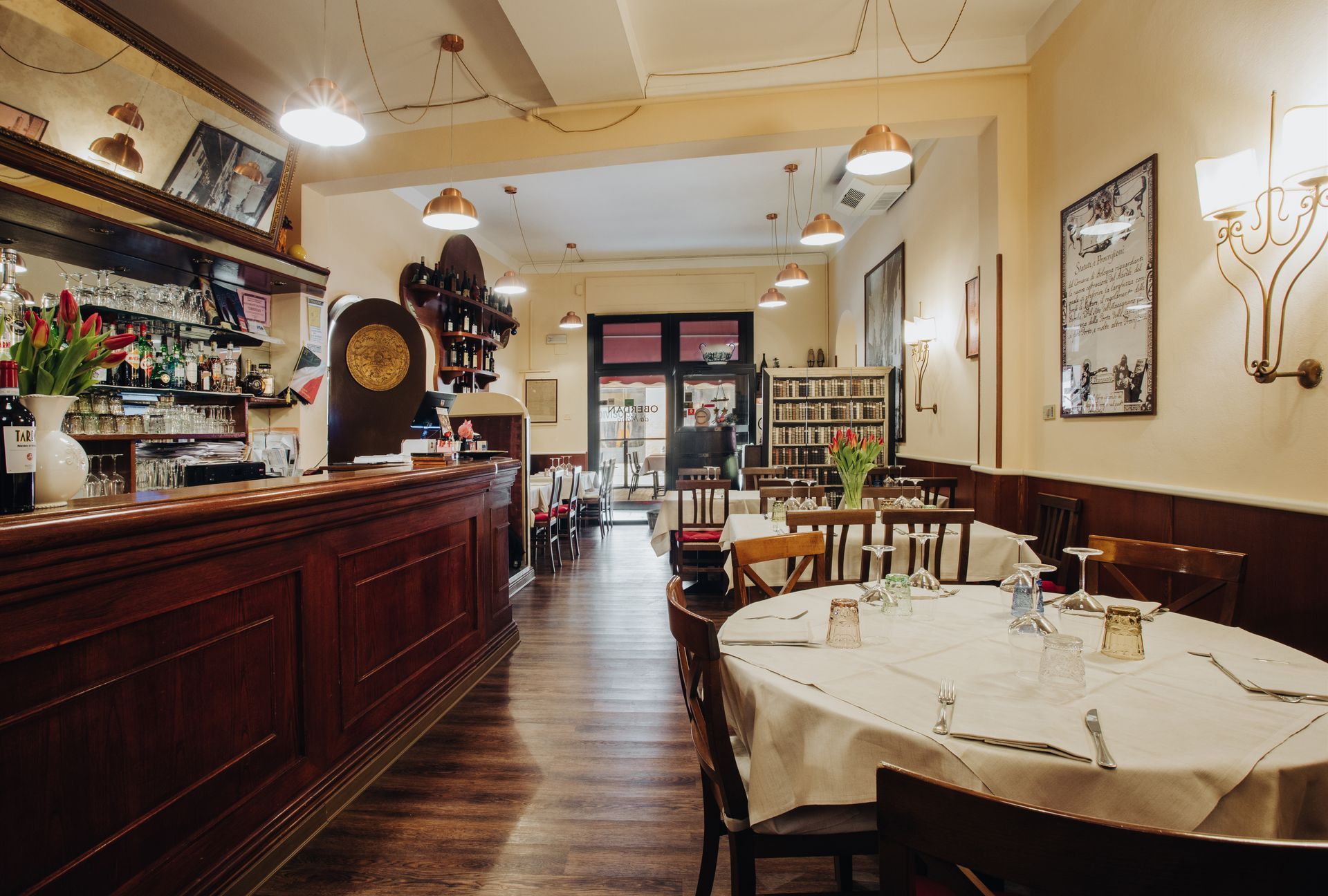 Interno di un ristorante con bar, tavoli e una porta che conduce all'esterno.