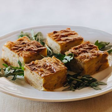 Quattro budini di pane quadrati su un piatto bianco con guarnizione di rucola.
