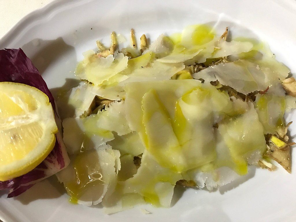 Piatto di verdure tagliate sottili con spicchio di limone e un filo d'olio.