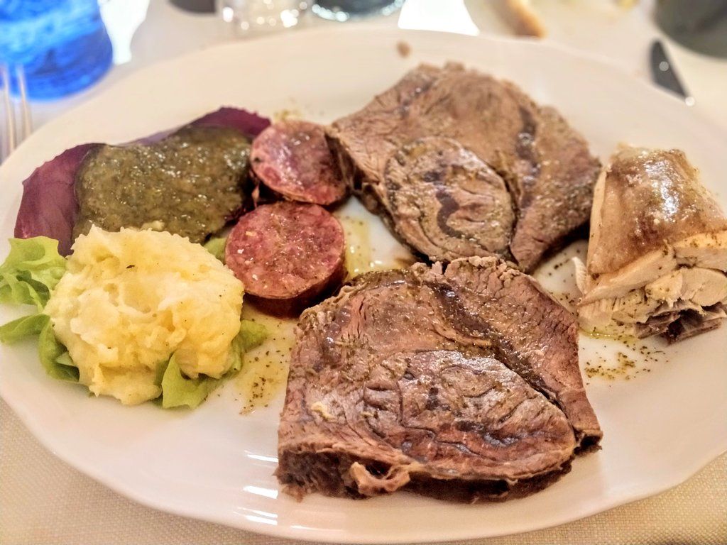 Piatto di cibo: carne, salsiccia, purè di patate, cibo viola e salsa.