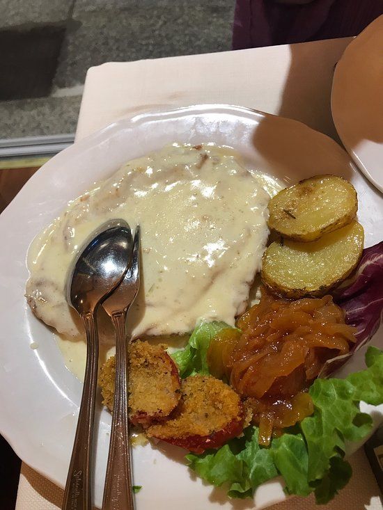 Piatto: cotoletta di pollo con salsa cremosa, patate, cipolle caramellate e verdure.