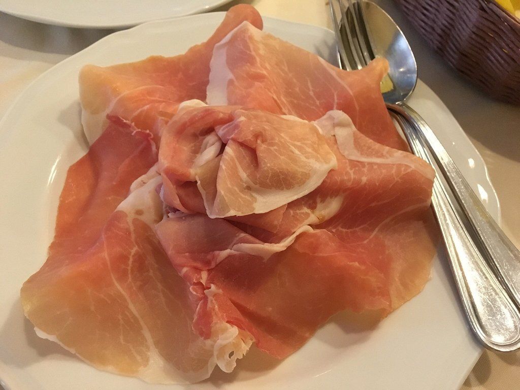 Piatto di prosciutto con forchetta e cucchiaio.