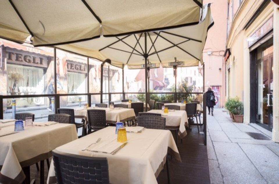 Posti a sedere all'aperto del ristorante con tavoli apparecchiati per mangiare sotto gli ombrelloni.