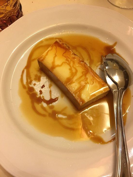 Dessert flan in salsa al caramello su un piatto bianco con due cucchiai.