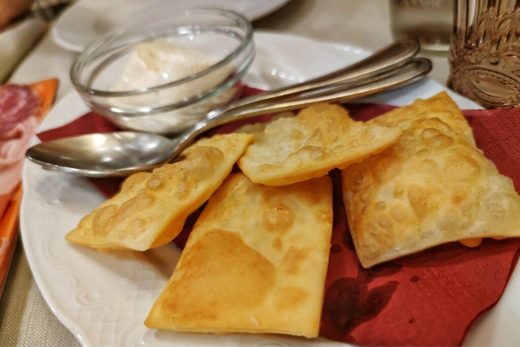 Pasta sfoglia fritta con salsa, servita su un piatto con posate.