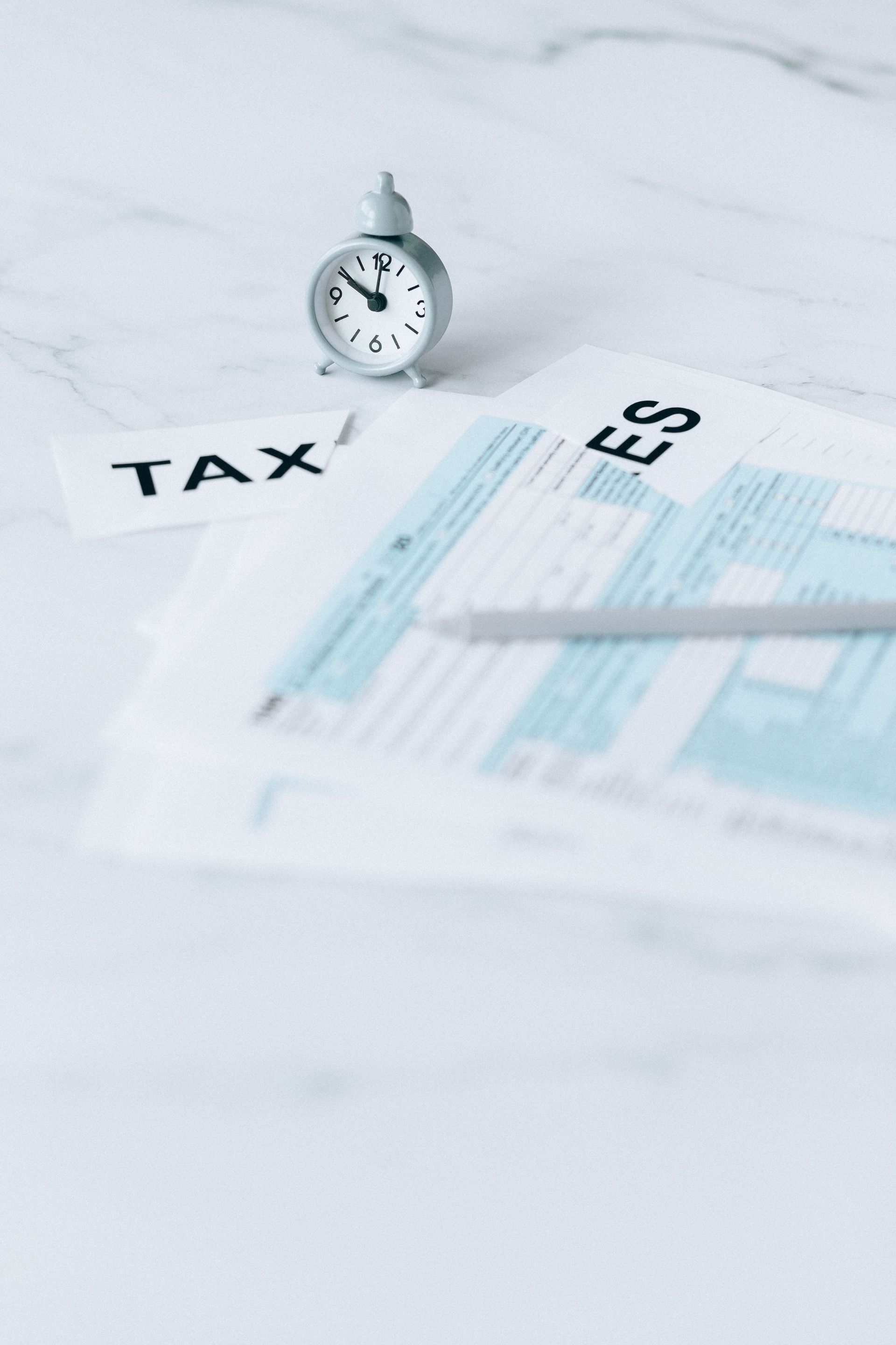 Tax forms with a small clock on a white desk