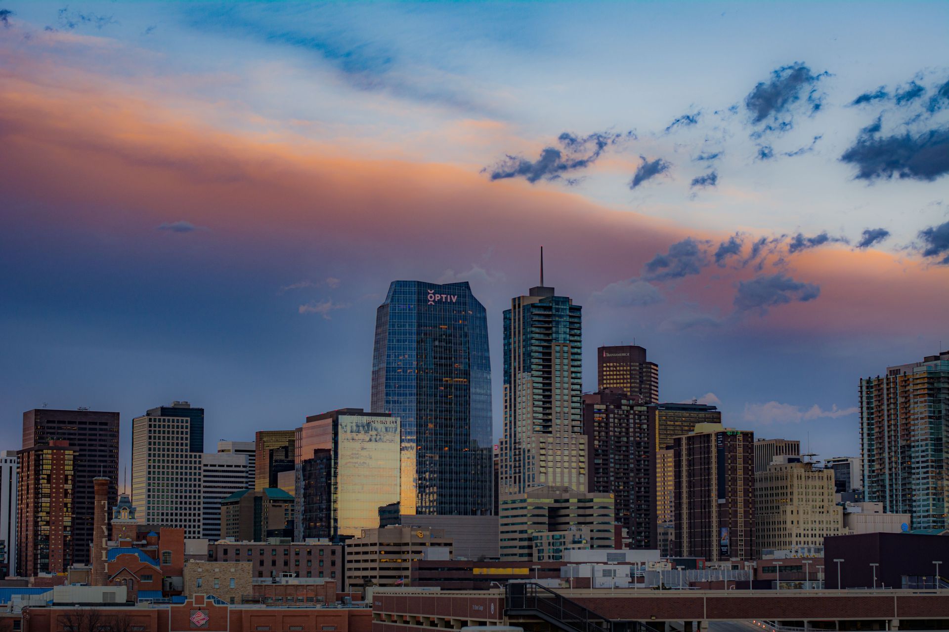 City skyline at dusk with tall buildings under a colorful pink and blue sky