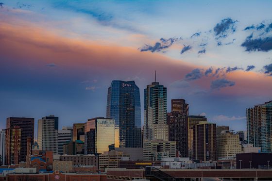 City skyline at dusk with tall buildings under a colorful pink and blue sky