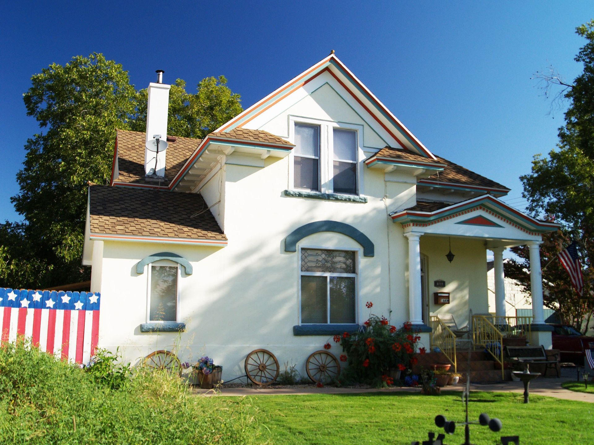 White house with porch and American flag display in a sunny front yard